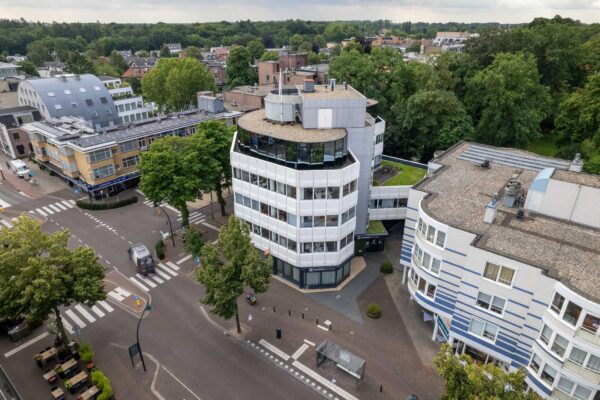 Luchtfoto van het kantoorgebouw aan de 1e Hogeweg in Zeist, omringd door bomen en stedelijke bebouwing.